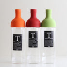 Three bottles with colored caps and clear bodies on a white background