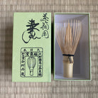 Matcha whisk with green box on a woven mat background