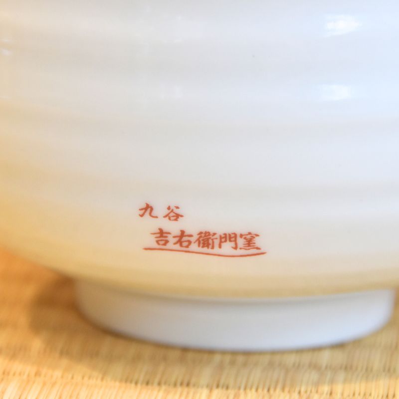 White ceramic bowl with red text on a woven mat