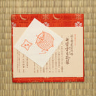 Close-up of red Nishijin silk brocade with overlapping shippo circles, snow crystals, crescent moons, and flowers.