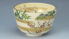 Angled view of the Kyo Ware matcha bowl showing cranes, pine, bamboo and plum decoration with gold leaf accents