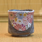 Ceramic cup with floral patterns on a woven mat background