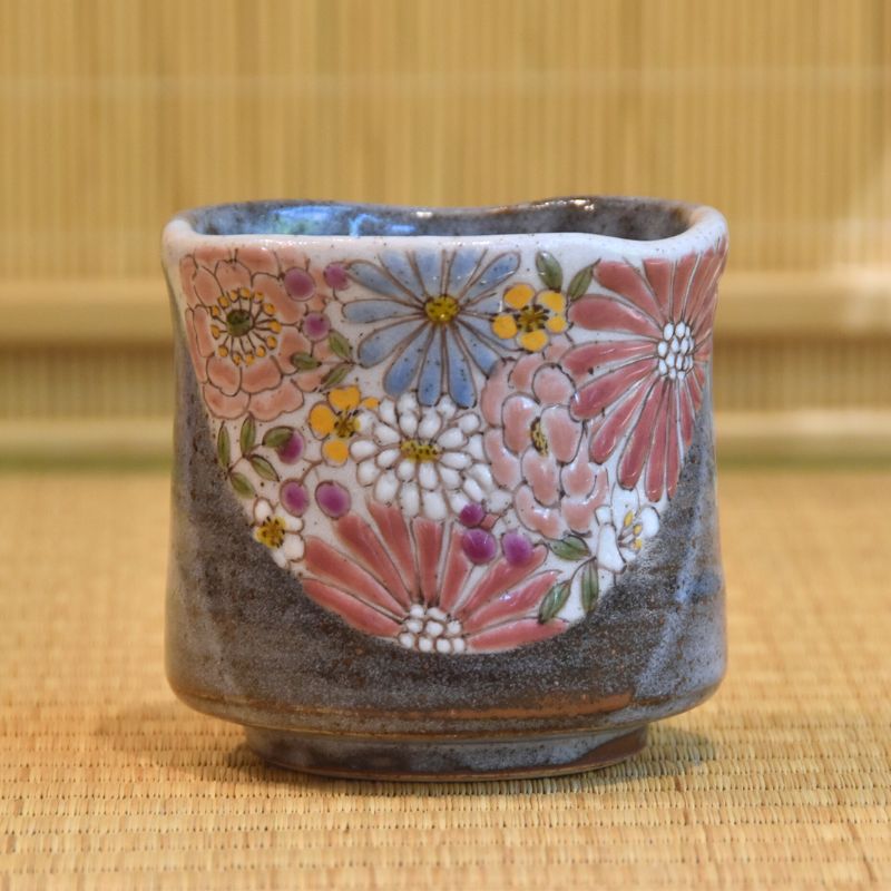 Ceramic cup with floral patterns on a woven mat background