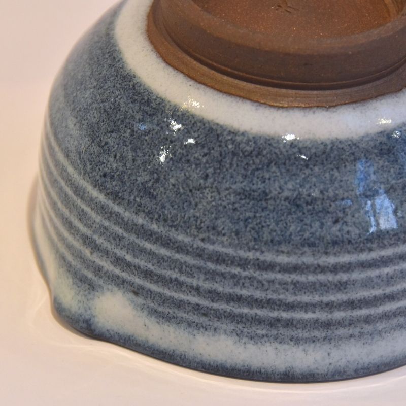 Close-up of the exposed brown foot and layered blue-and-white glaze on the underside of the handcrafted Tamba Ware bowl.