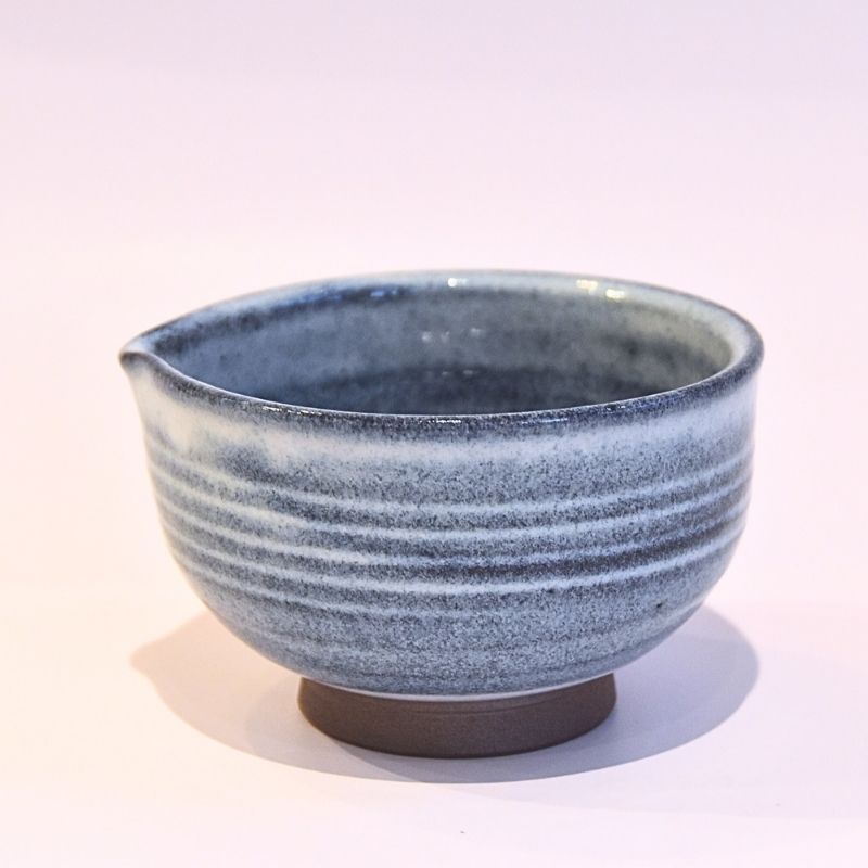 Front view of a handcrafted Tamba Ware katakuchi matcha bowl with layered denim-blue glaze, white horizontal bands, a pouring spout, and an exposed brown foot.