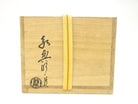 Exterior of the original wooden storage box with Japanese calligraphy, a circular seal, and a yellow securing cord.