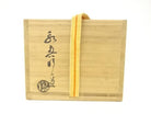 Exterior of the wooden storage box with Japanese calligraphy, a circular seal, and a yellow securing cord for the Eiko Meido Raku matcha bowl.