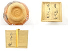 Detail collage showing the circular foot and firing colors of the Raku chawan together with Japanese calligraphy on its wooden storage box.