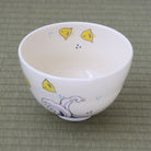Top interior view of the Eishin Kato Nami Chidori matcha bowl showing yellow Chidori birds inside the white glazed bowl and stylized waves on the exterior