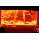 A close-up view inside a glowing furnace or kiln, showing stacks of circular ceramic plates or tiles arranged in compartments among glowing yellow-orange heat-resistant materials.