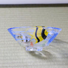 Side view of shallow glass matcha bowl with colorful blue and yellow angelfish design