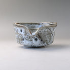 Front view of the Mino Ware katakuchi matcha bowl with its V-shaped pouring spout centered above the speckled white and gray surface.
