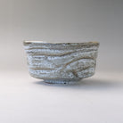 Rear profile of the Mino Ware matcha bowl showing its low rounded form, horizontal ridges, and snow-washed gray and white glaze.