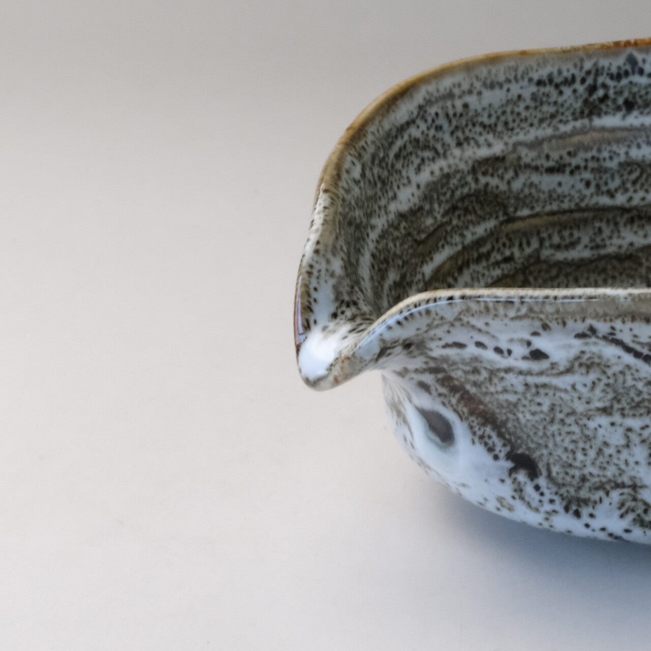 Close-up of the pouring spout and layered gray, white, and charcoal glaze on the Mino Ware katakuchi matcha bowl.