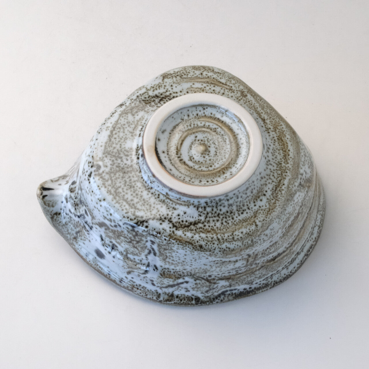 Underside view of the gray and white Mino Ware katakuchi bowl showing the circular foot ring and spiral glaze around the base.