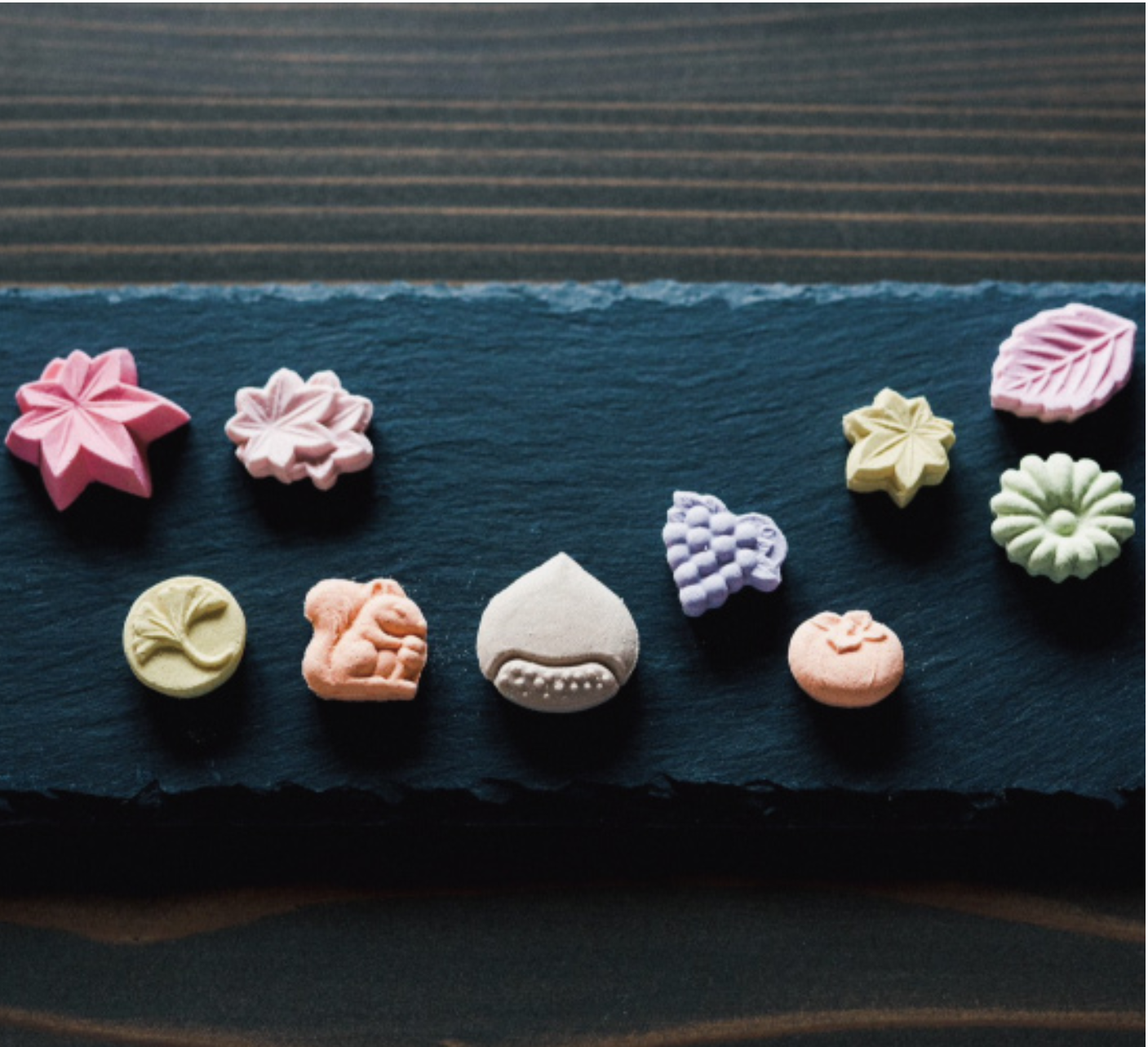 Assorted colorful flower-shaped cookies on a dark surface