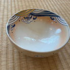 Top view of the Hokusai-inspired matcha bowl showing its cream interior and layered cobalt-blue and ochre-gold waves around the rim.