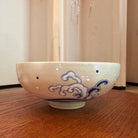 Hokusai-inspired Kyo Ware matcha bowl displayed on a wooden surface beside a softly lit Japanese-style window.