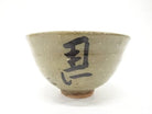 Front view of the Izumino Ware matcha bowl showing bold black Hidari-Uma calligraphy against an earthy ash-green speckled glaze.