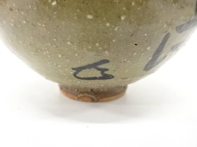 Close-up of the lower exterior showing a small dark painted mark, pale speckled glaze, and warm exposed clay around the foot.