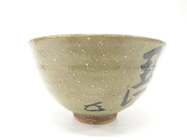 Side view of the pre-owned chawan showing its softly rounded form, olive-gray glaze variation, and painted details near the foot.