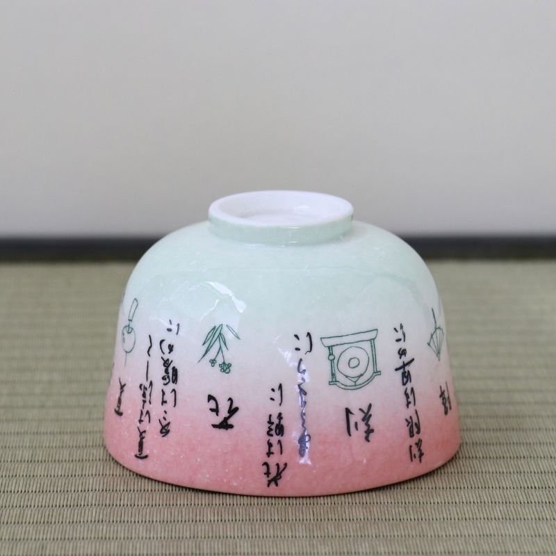 Underside view of the Kagetsu Kiln Rikyu Shichisoku matcha bowl showing its ceramic foot and calligraphy continuing around the pink and pale green exterior