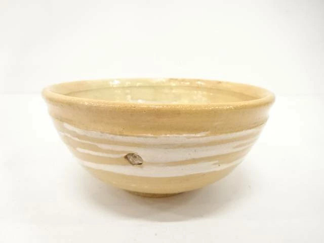 Front view of the Kahei Shima Raku chawan showing its softly irregular rim and layered sand, cream, and ivory glaze.
