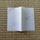 White paper with cloud and leaf drawings on a woven mat background