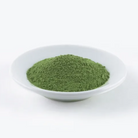 Green powder in a white bowl on a white background