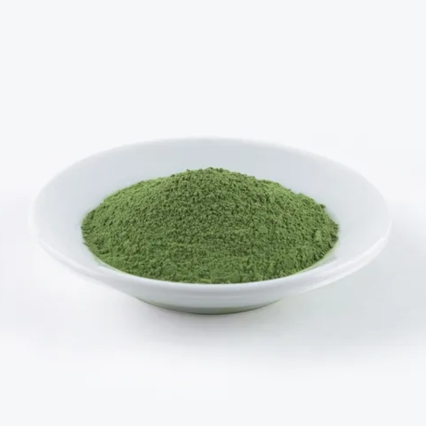 Green powder in a white bowl on a white background