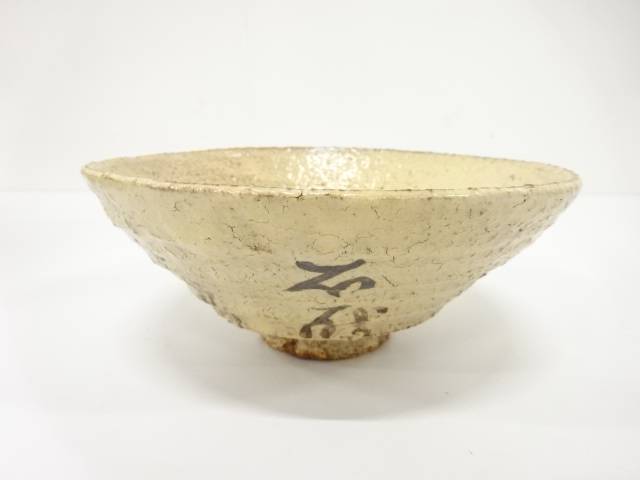 Front view of the Kaneko Sofu Hagi Ware chawan showing black calligraphic brushwork on a warm ivory speckled glaze.
