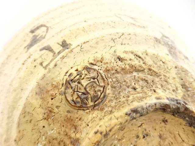Close-up of the underside showing the textured Hagi clay, circular foot, firing variation, and impressed potter's mark.