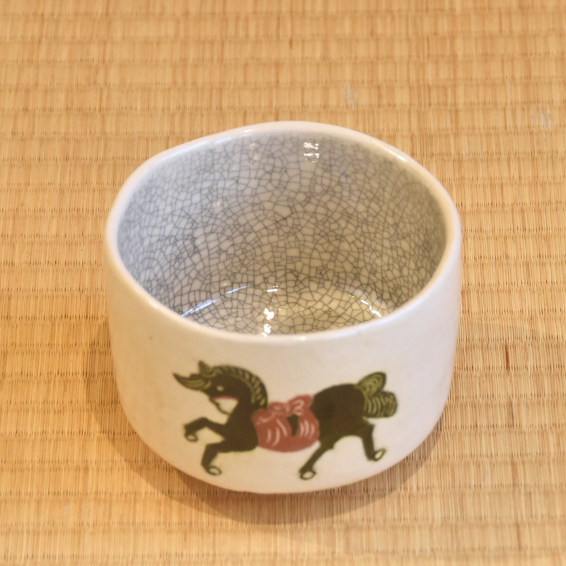 Angled top view of the Kawasaki Waraku matcha bowl showing its softly speckled interior, uneven rim, and horse decoration on the exterior.