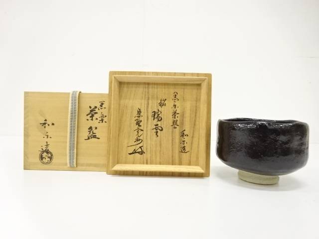 Pre-owned Kawasaki Waraku Black Raku matcha bowl displayed beside its inscribed wooden storage box and accompanying box.