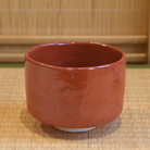 Back view of the Kawasaki Waraku matcha bowl highlighting the softly lustrous red glaze and hand-shaped surface.