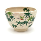 Front view of a hand-painted Kiyomizu Ware matcha bowl featuring a colorful kingfisher among fresh green maple leaves.