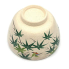 Underside of the handcrafted matcha bowl showing the foot ring and green maple branches wrapping around the exterior.