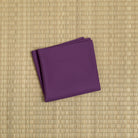 Folded plum color silk fukusa displayed on tatami mat for Japanese tea ceremony practice, handcrafted by Kitamura Tokusai.