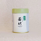A can of TOMOTAKE Marukyu Koyamaen Matcha powder, with a predominantly white label and green lid, placed against a patterned background.