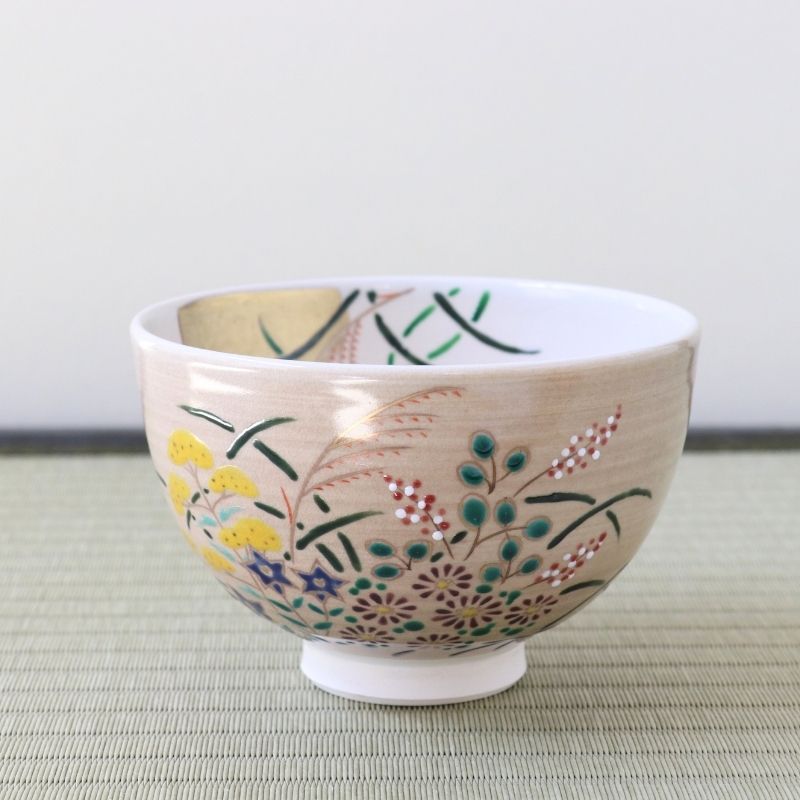 Hand-painted Kyo-yaki matcha bowl featuring colorful Akikusa autumn grasses and flowers beneath a gold leaf full moon on a soft pink glaze
