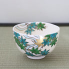 Hand-painted Kyo-yaki matcha bowl featuring fresh green Aokaede maple leaves with gold leaf accents on a warm ivory glaze