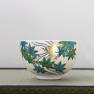 Hand-painted Kyo-yaki matcha bowl featuring fresh green Aokaede maple leaves with gold leaf accents on a warm ivory glaze