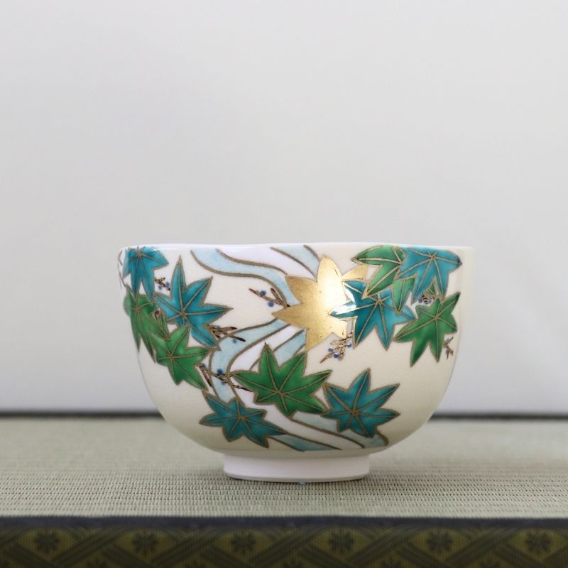 Hand-painted Kyo-yaki matcha bowl featuring fresh green Aokaede maple leaves with gold leaf accents on a warm ivory glaze