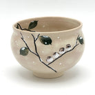 Hand-painted Kyo-yaki matcha bowl featuring the Eda ni Suzume motif with small sparrows perched on a dark branch, green leaves, and white accents on a warm beige glaze