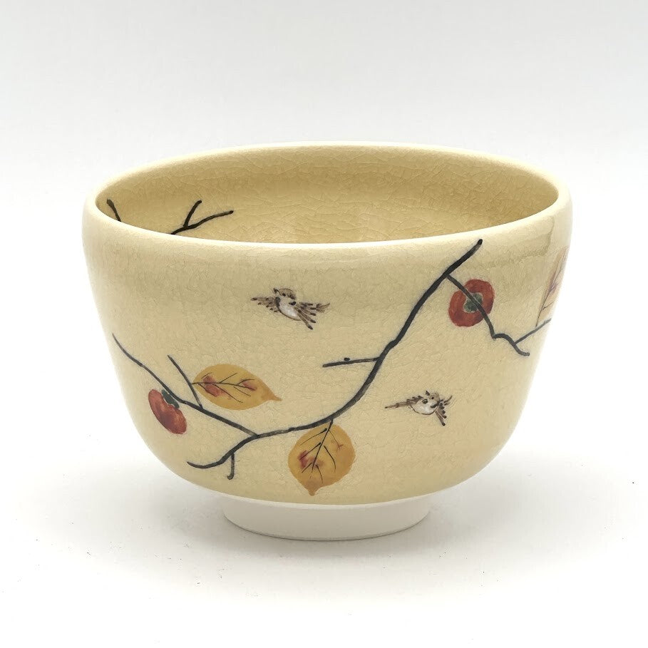 Hand-painted Kyo-yaki matcha bowl featuring the Kaki ni Suzume motif with ripe persimmons, autumn leaves, sparrows, and dark branches on a warm beige glaze