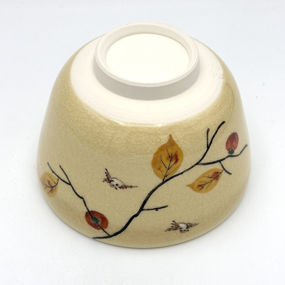 Underside view of the Kyo-yaki Kaki ni Suzume matcha bowl showing its ceramic foot and hand-painted persimmon branches, leaves, and sparrow details