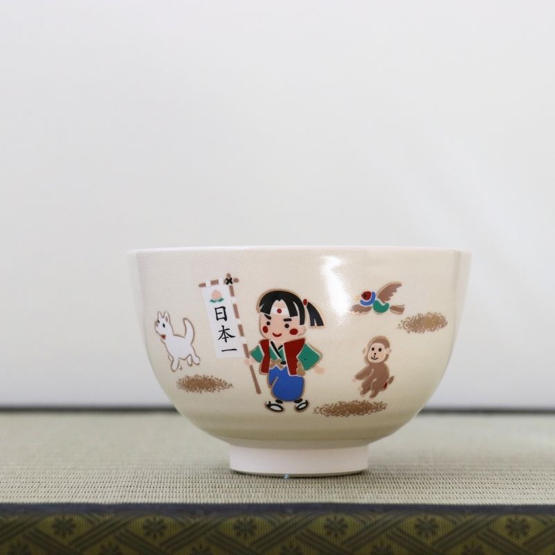 Hand-painted Kyo-yaki matcha bowl featuring Momotaro, the legendary Japanese Peach Boy, with his animal companions on a warm ivory glaze
