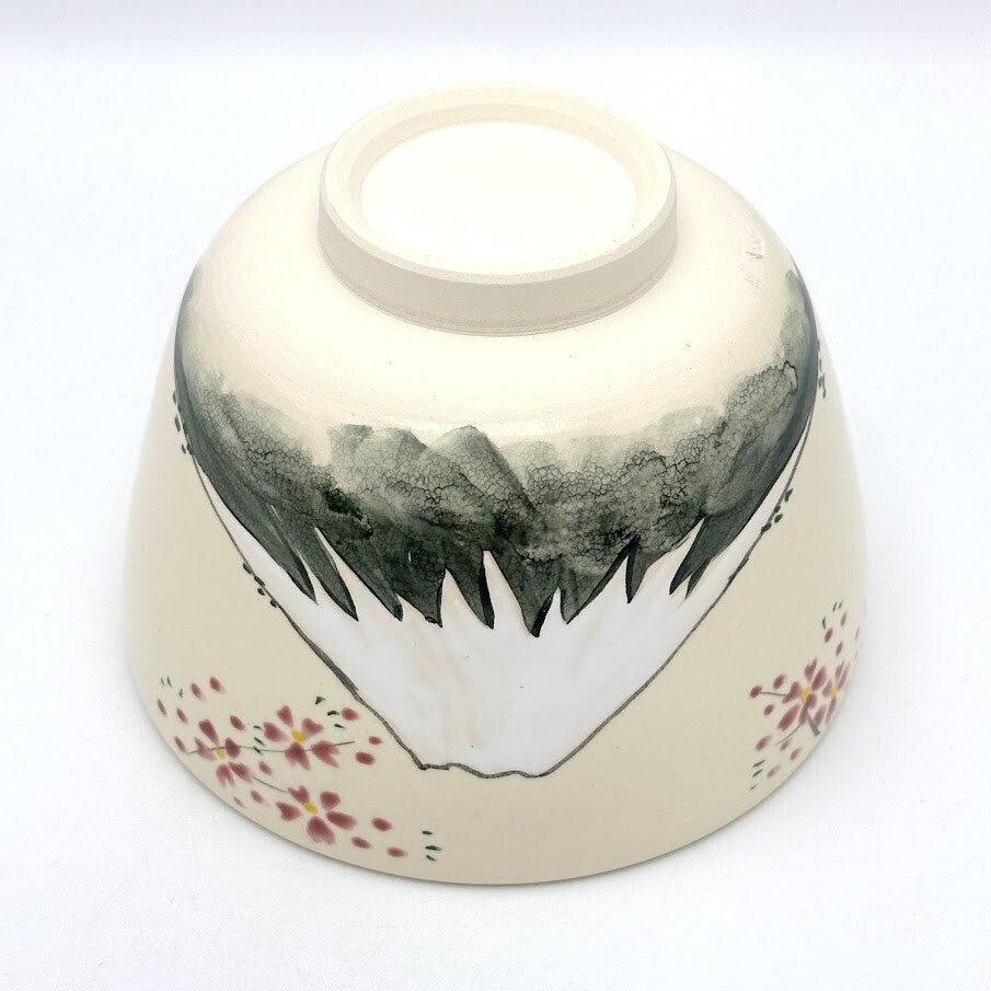 Underside view of the Kyo-yaki Mt. Fuji chawan showing its ceramic foot, hand-painted mountain landscape, and pink blossom decoration