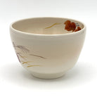 Angled view of the Kyo-yaki red ivy and sparrow chawan showing its rounded profile, ivory glaze, and partial hand-painted autumn decoration
