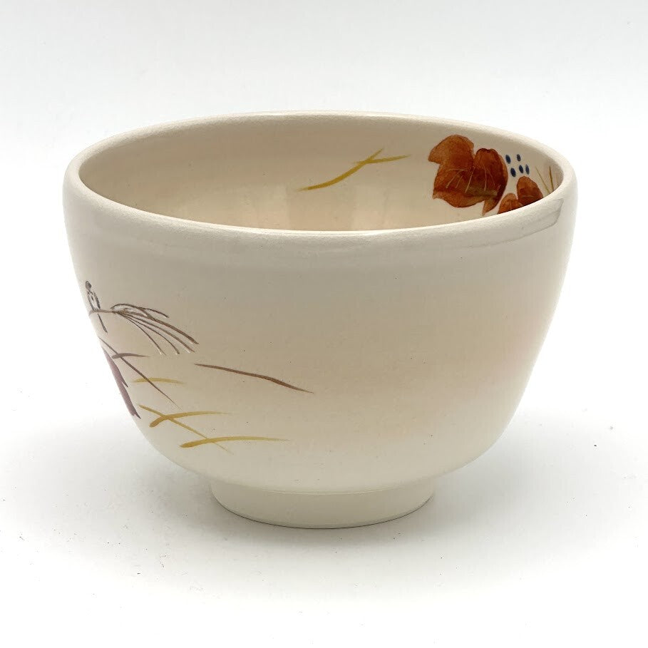 Angled view of the Kyo-yaki red ivy and sparrow chawan showing its rounded profile, ivory glaze, and partial hand-painted autumn decoration